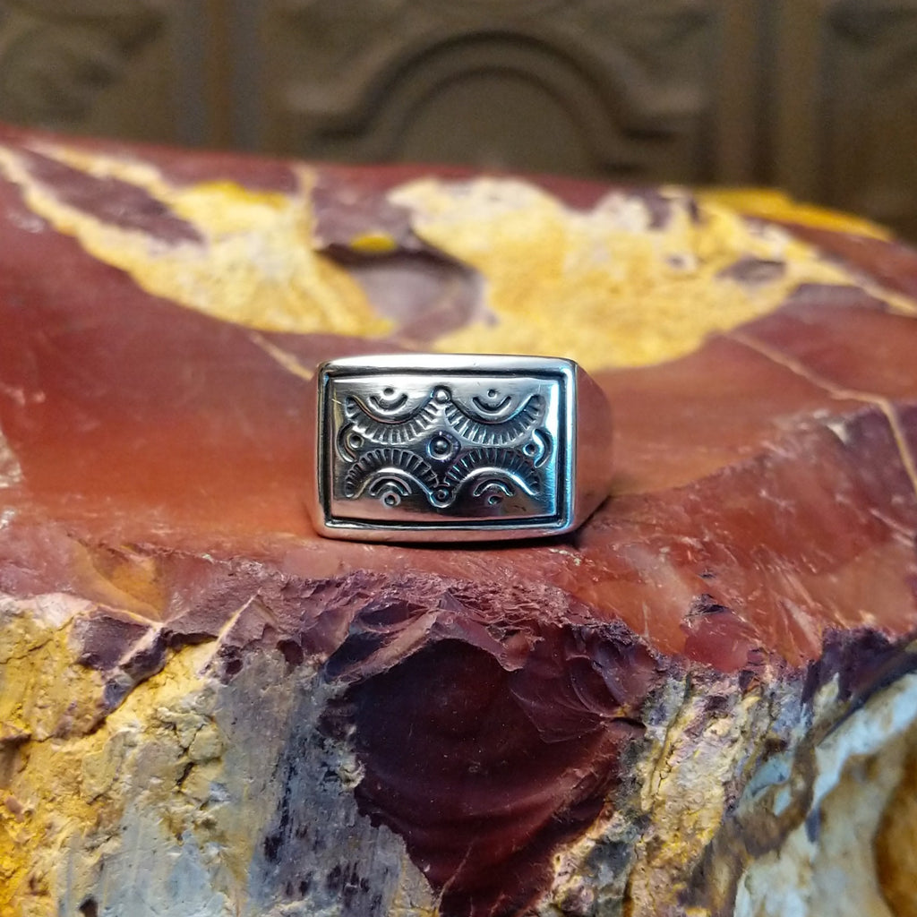Sterling silver ring with a raised bezel featuring intricate designs.