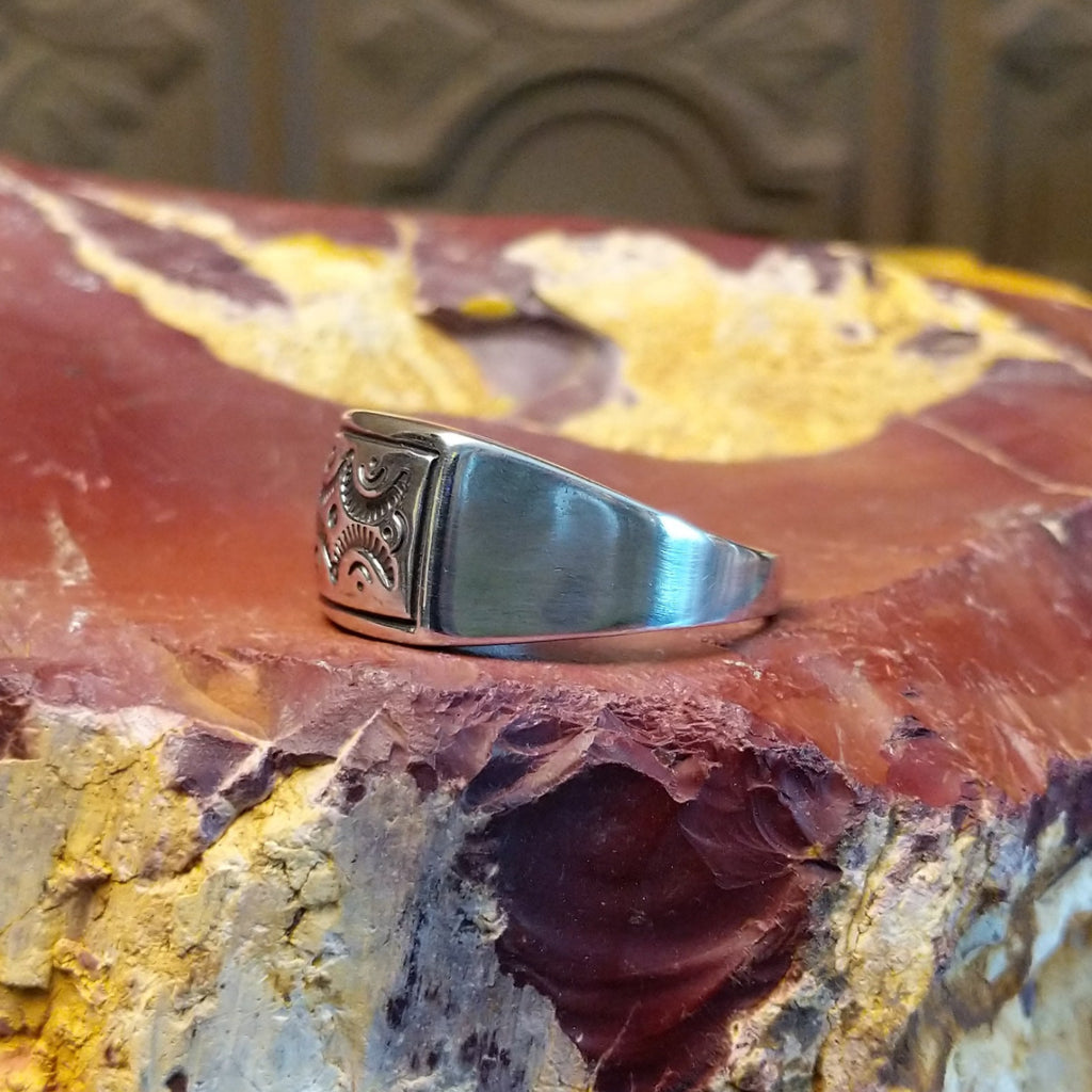 Sterling silver ring with a raised bezel featuring intricate designs.