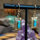 14kt gold Navajo dangle earrings featuring rectangular turquoise inlay with geometric line details and textured gold frames.