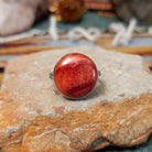 Navajo sterling silver ring by N.A. featuring a round red spiny oyster shell cabochon with natural color variations in a smooth silver bezel.