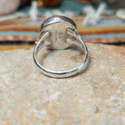 Navajo sterling silver ring by N.A. featuring a round red spiny oyster shell cabochon with natural color variations in a smooth silver bezel; underside view.