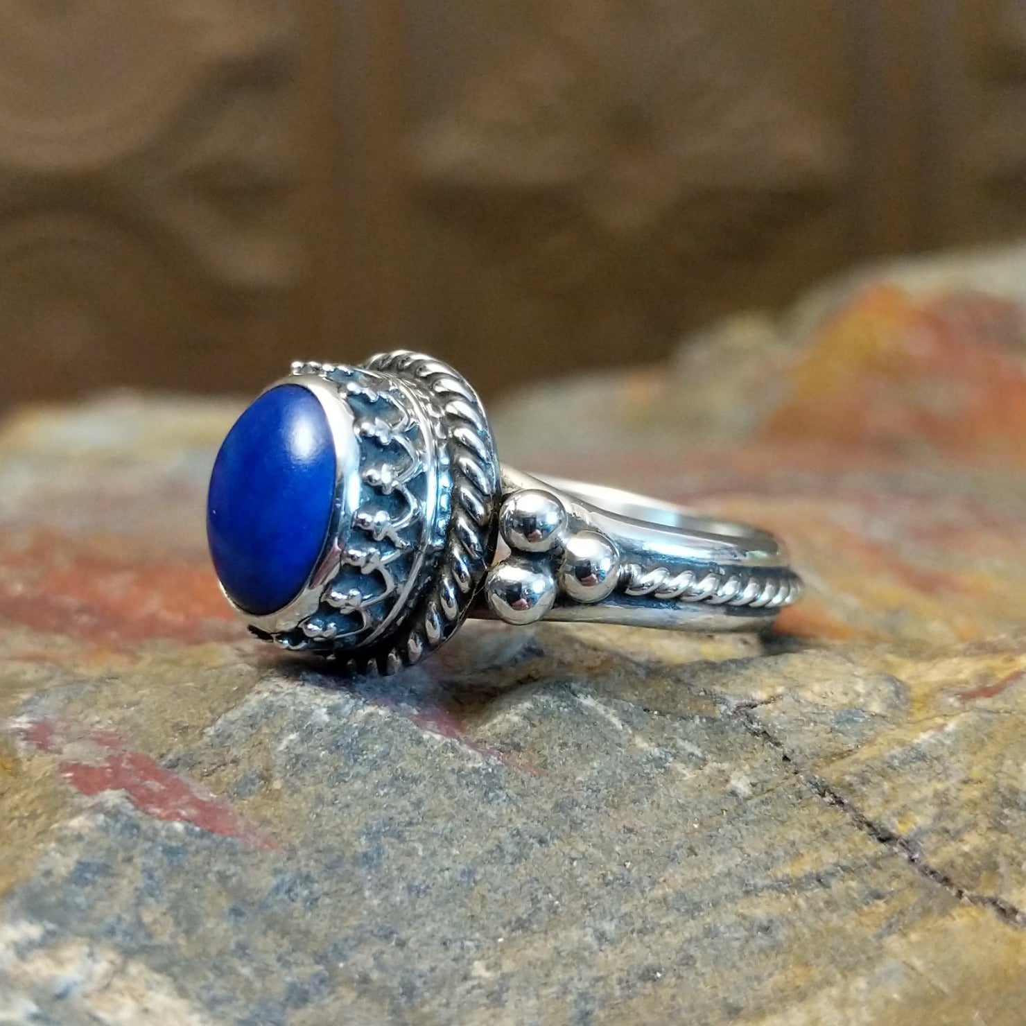 Sterling silver ring with lapis set in the round bezel, framed by twisted rope and dotted accents on the band.
