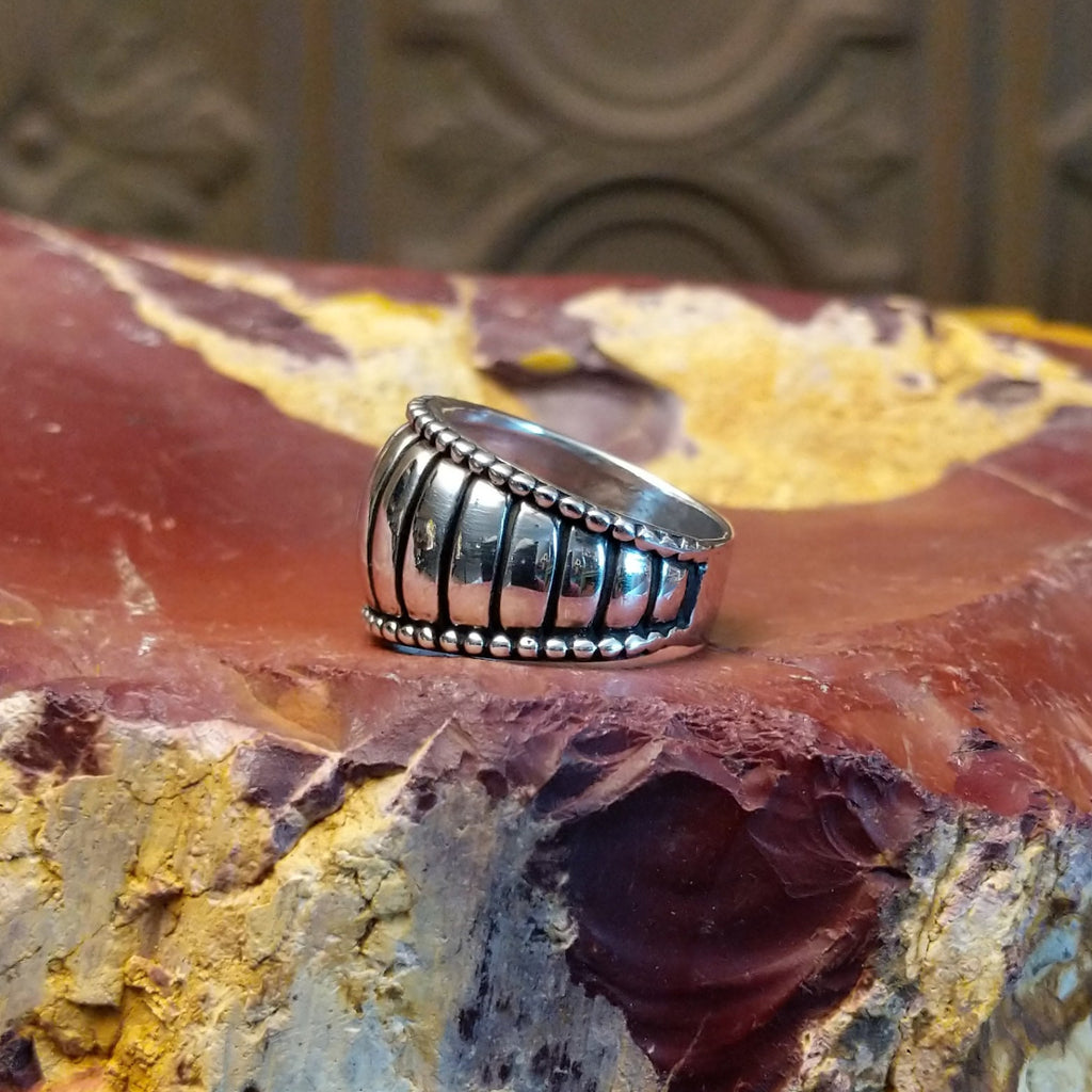 Sterling silver ring with a ribbed effect and dotted edges.