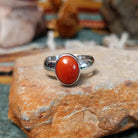 Navajo sterling silver ring by W.B.V. featuring a smooth oval red coral cabochon set in a polished silver bezel and band.