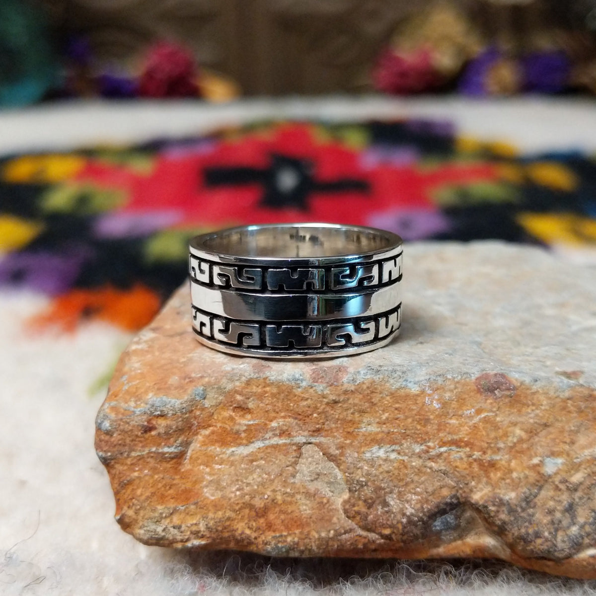Distinctive Navajo Silver Ring featuring a wide polished silver band with repeating geometric patterns, dark oxidized accents, and a smooth central stripe.