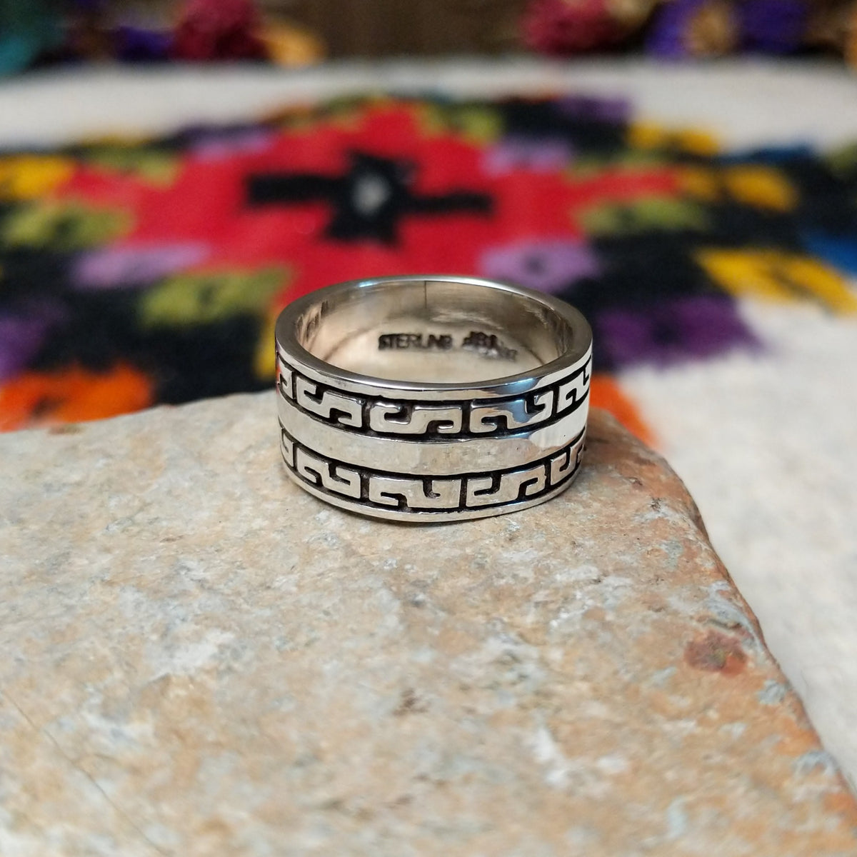 Distinctive Navajo Silver Ring featuring a wide polished silver band with repeating geometric patterns, dark oxidized accents, and a smooth central stripe.