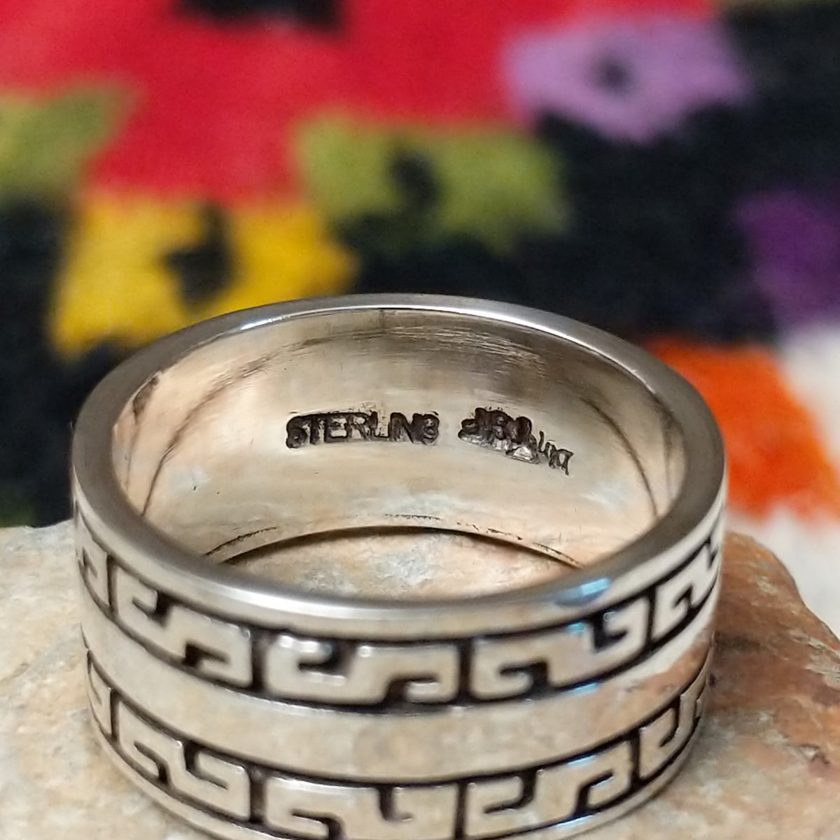 Distinctive Navajo Silver Ring featuring a wide polished silver band with repeating geometric patterns, dark oxidized accents, and a smooth central stripe.