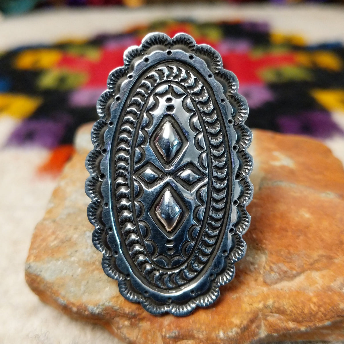 Navajo Silver Concho Ring with an elongated oval shape, raised diamond motifs, detailed stamped silverwork, oxidized accents, and a scalloped border.