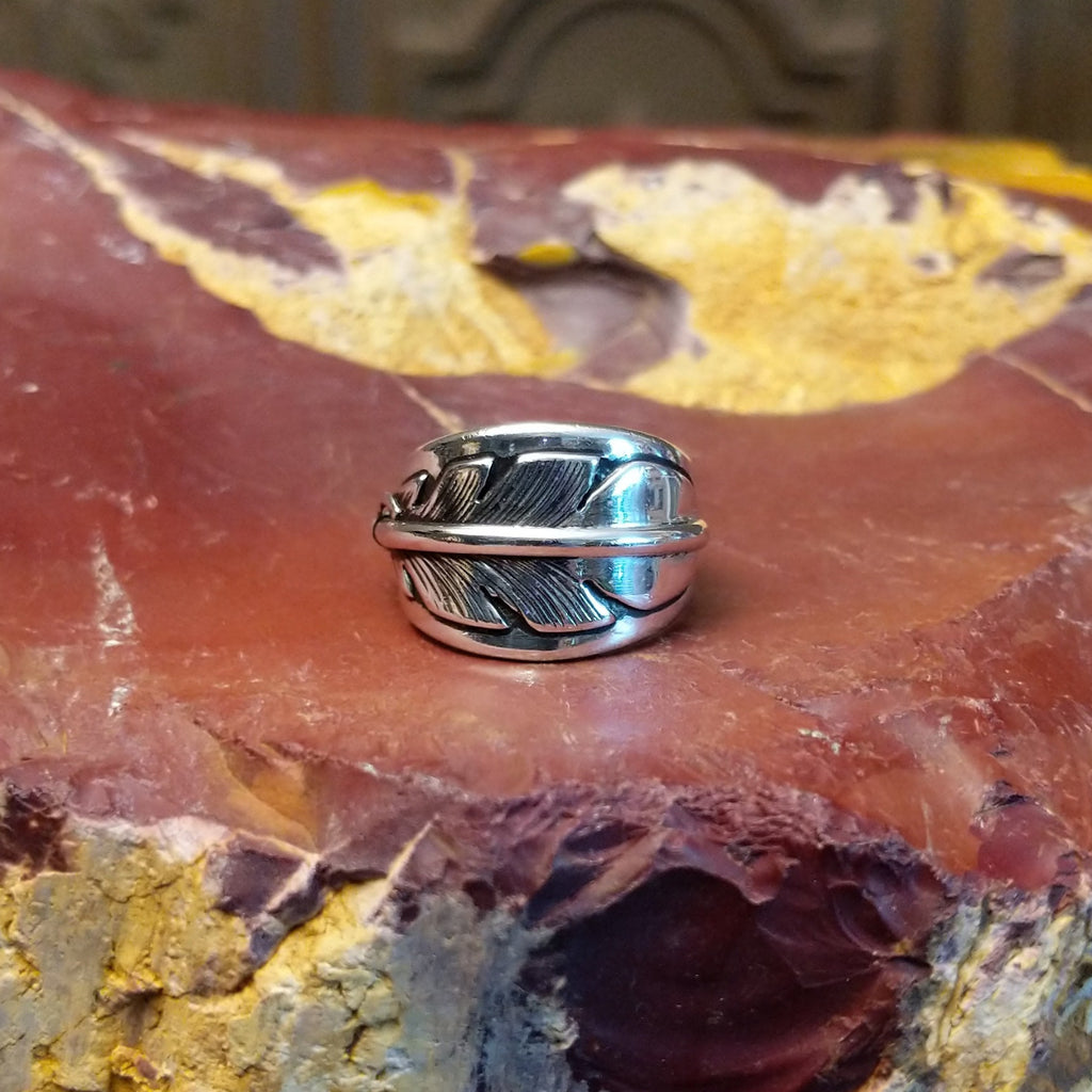 Sterling silver ring with a feather motif curved along the band.
