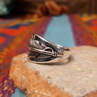Navajo Silver Feather Ring by L.P. featuring a detailed engraved feather with a raised curved quill across a wide, polished silver band; side view.