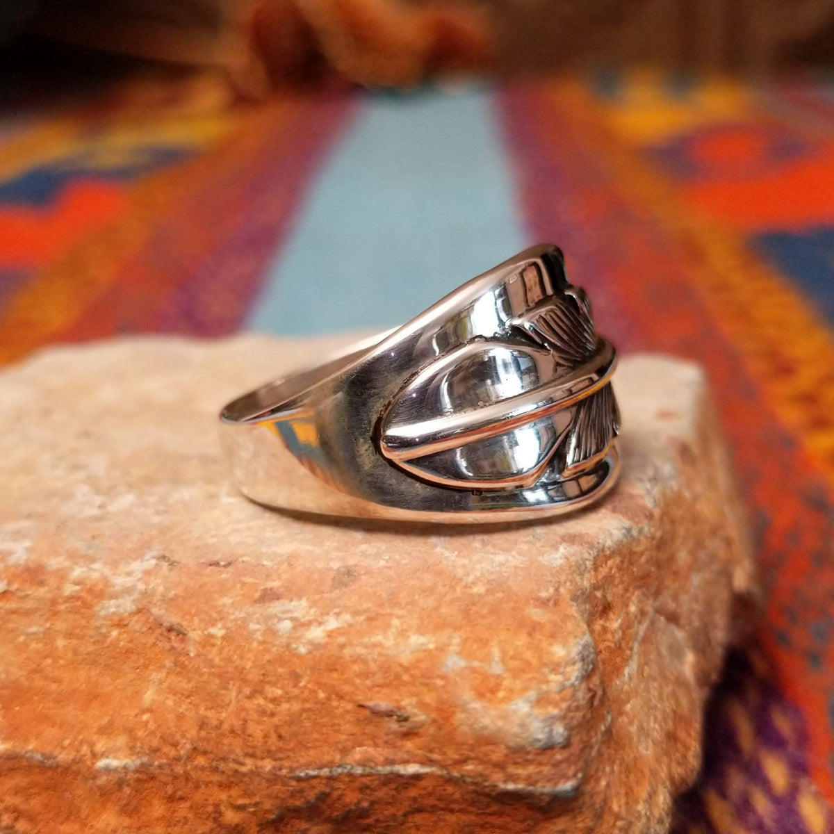 Navajo Silver Feather Ring by L.P. featuring a detailed engraved feather with a raised curved quill across a wide, polished silver band; side view.
