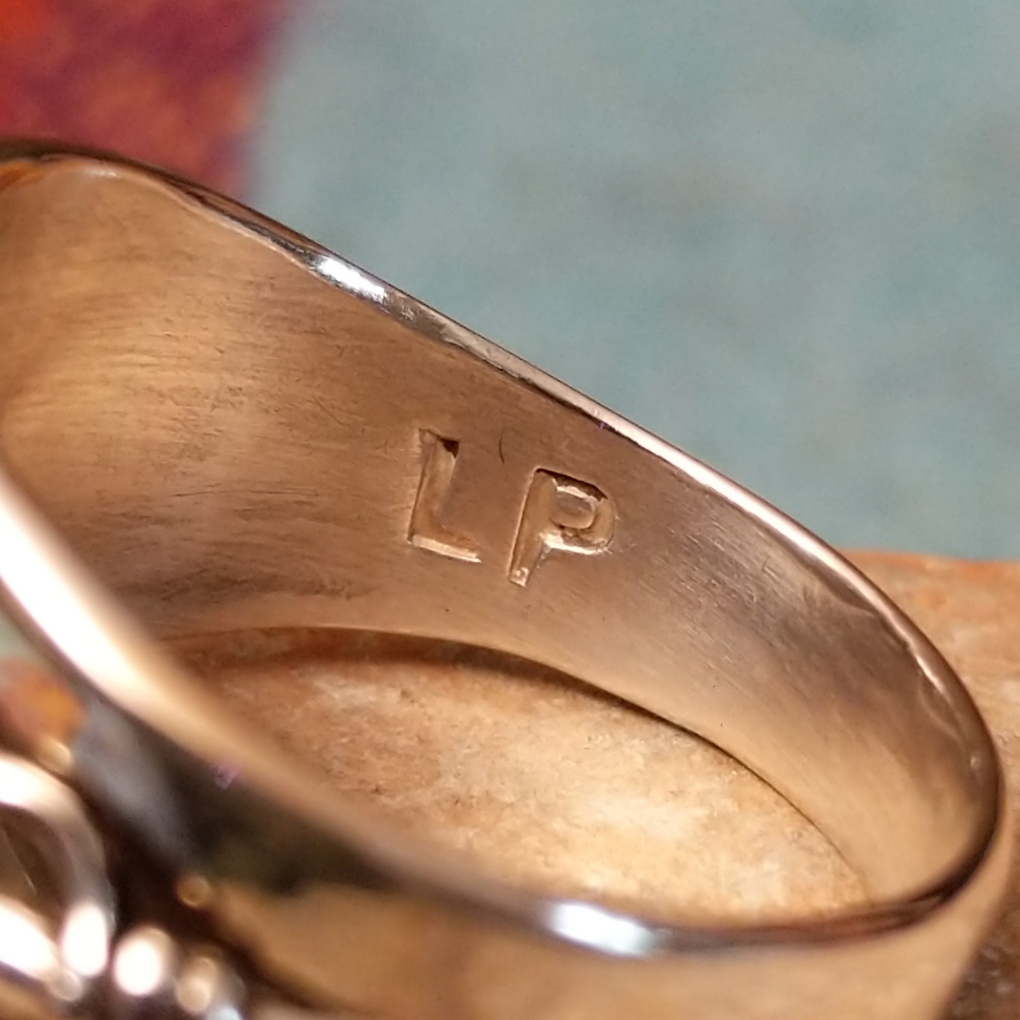 Navajo Silver Feather Ring by L.P. featuring a detailed engraved feather with a raised curved quill across a wide, polished silver band; artisan stamp.