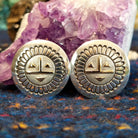 The earrings showing detailed stamping, geometric gold facial accents, and polished silver finish.
