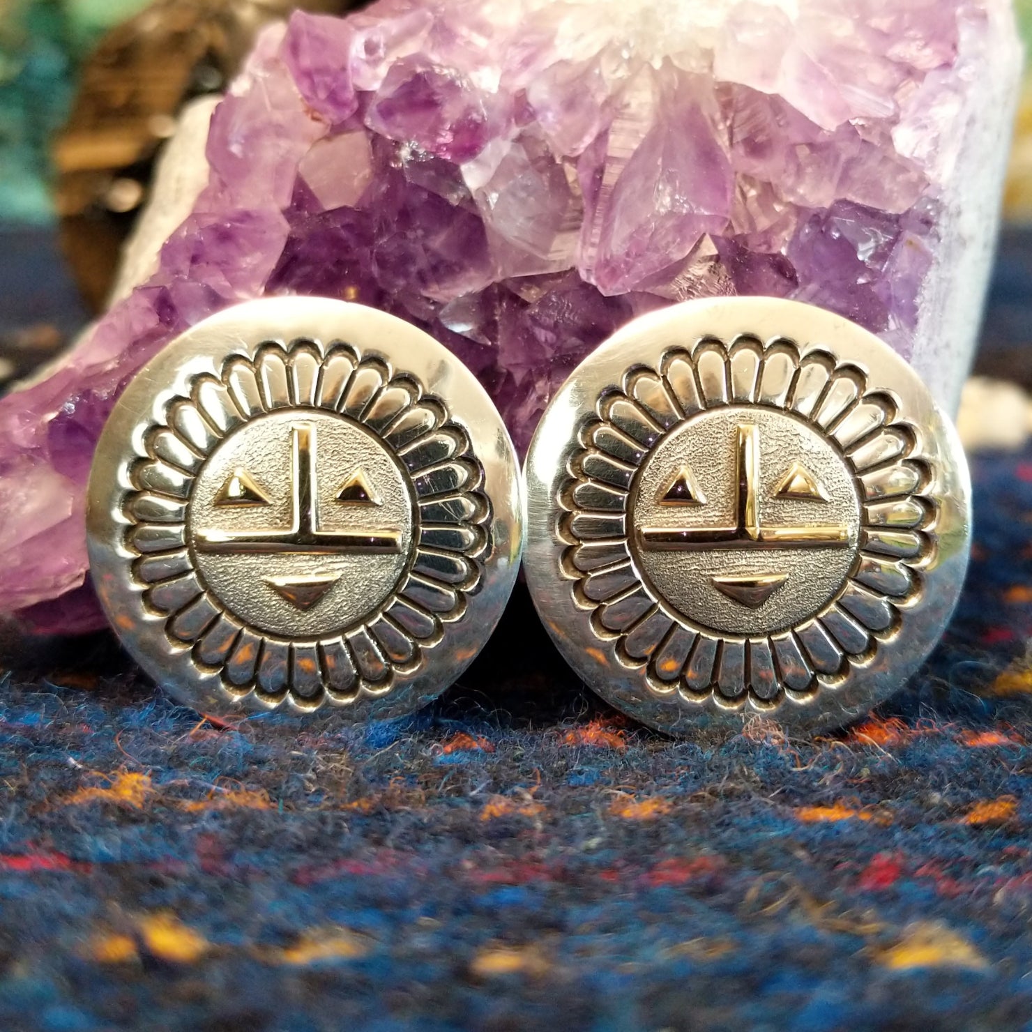 The earrings showing detailed stamping, geometric gold facial accents, and polished silver finish.