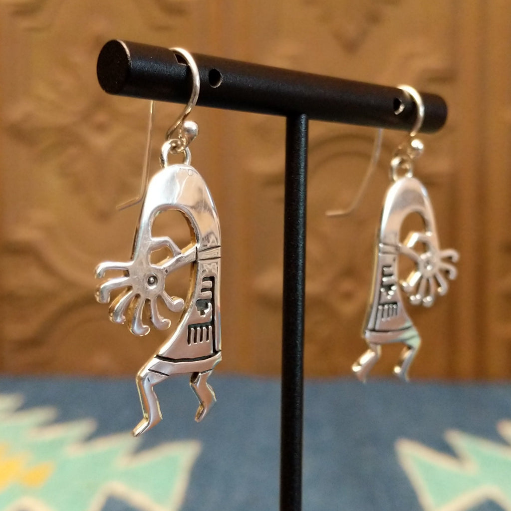Sterling silver made into kokopelli figures with intricate designs as dangle earrings.