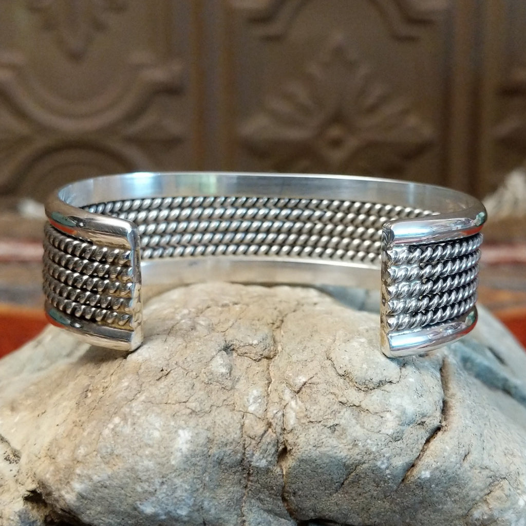 Sterling silver cuff with layered rope accents and polished finish.