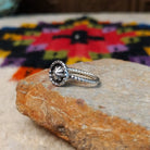 This Navajo Silver Star Ring features a round sterling silver face with a polished starburst design, dark oxidized background, beaded border, and textured silver band; side view.