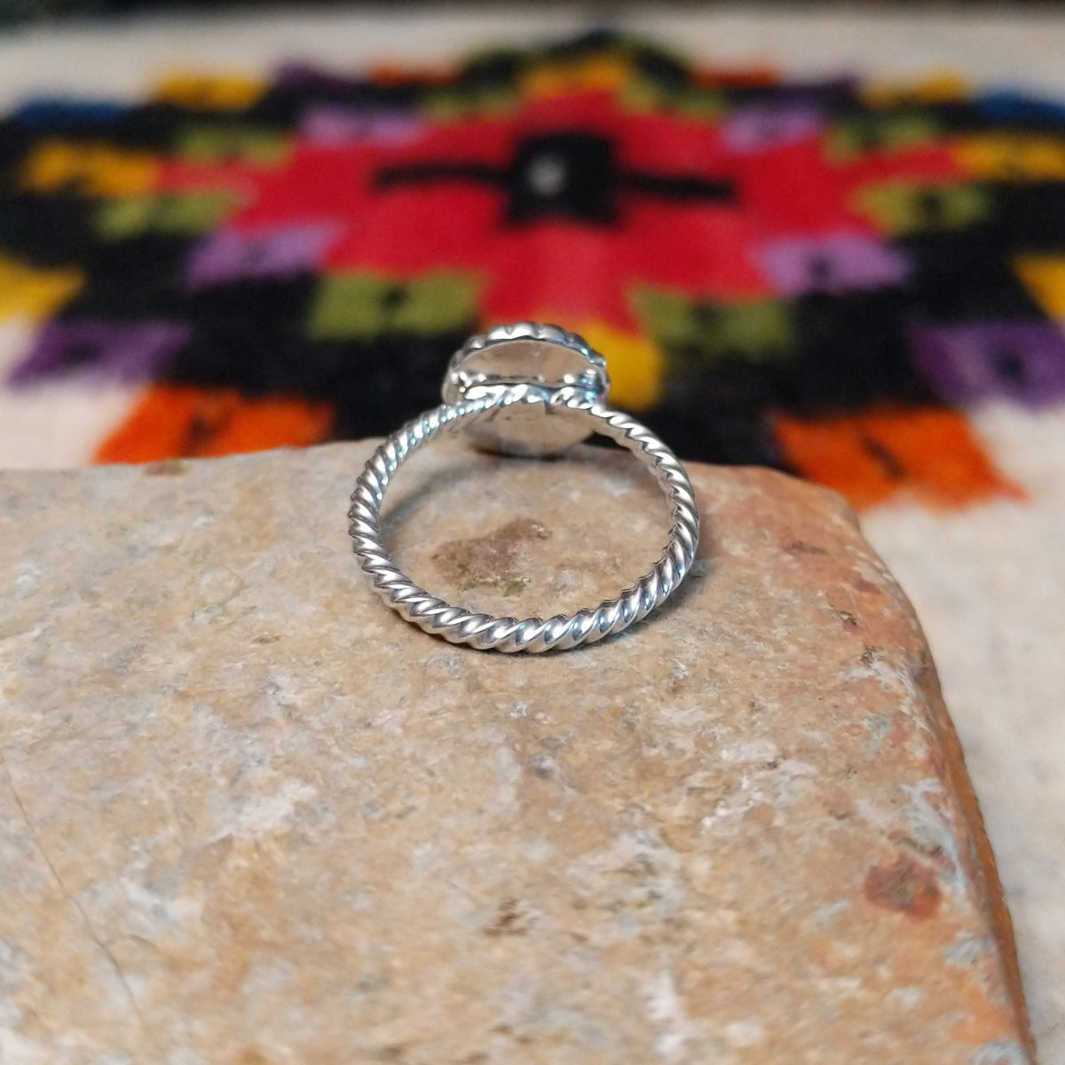 This Navajo Silver Star Ring features a round sterling silver face with a polished starburst design, dark oxidized background, beaded border, and textured silver band; underside view.