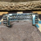 Navajo Sonoran Gold turquoise cuff by H.R.M., featuring an oval blue and green Sonoran Gold turquoise stone with natural matrix set in a handcrafted sterling silver cuff with twisted chain accents; underside view.