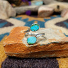 Handcrafted Navajo sterling silver bypass ring featuring two oval Sonoran Gold turquoise cabochons in smooth bezel settings, with vibrant blue and green natural turquoise on a polished open-band design.