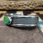 Navajo Sonoran Gold turquoise cuff by H.R.M. with a natural blue-green turquoise stone on a triple-shank sterling silver cuff; side view.