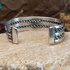 Sterling silver cuff with turquoise set in an oval bezel and chain-like designs on the band.