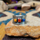 Navajo sterling silver textured band ring with three square gemstones in yellow, red, and blue.