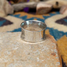 Navajo sterling silver textured band ring with three square gemstones in yellow, red, and blue; underside view.