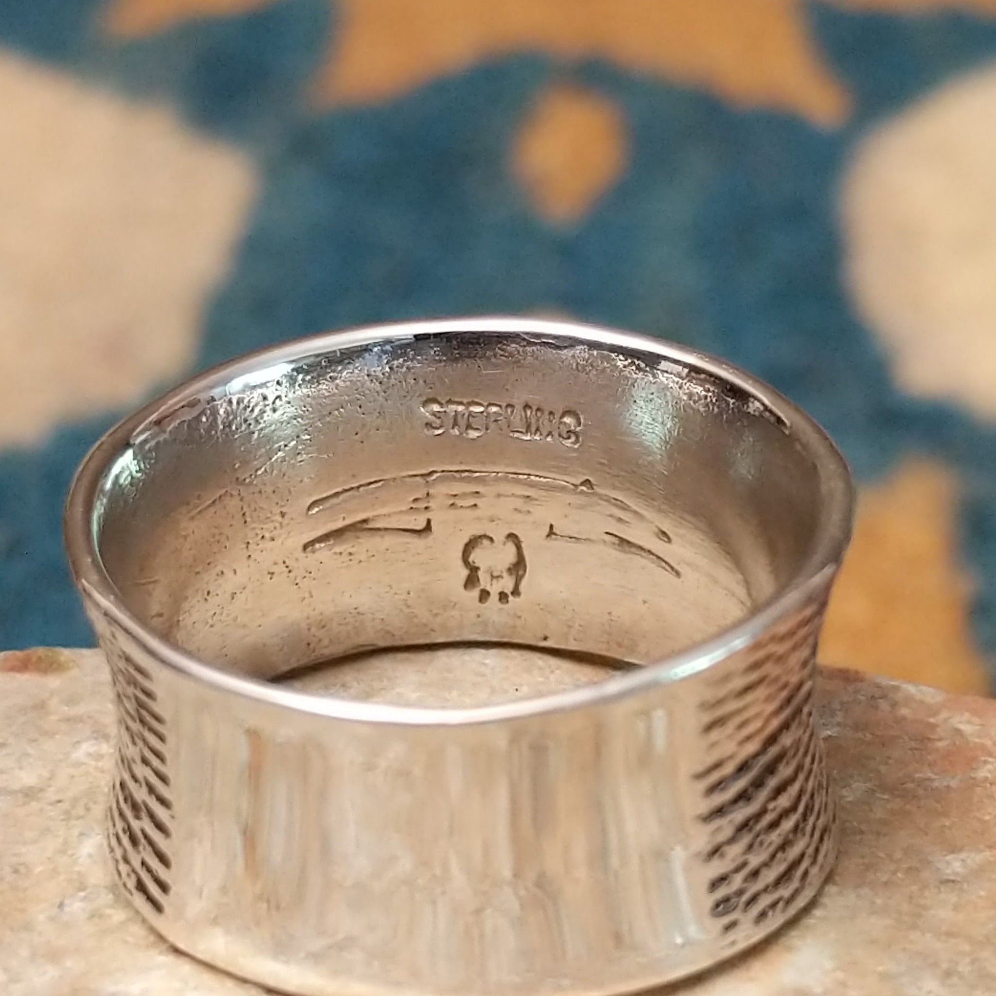 Navajo sterling silver textured band ring with three square gemstones in yellow, red, and blue; artisan and Sterling Silver stamp.