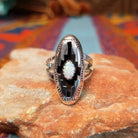 Navajo silver shadowbox ring by P. with stepped design and manmade opal center.