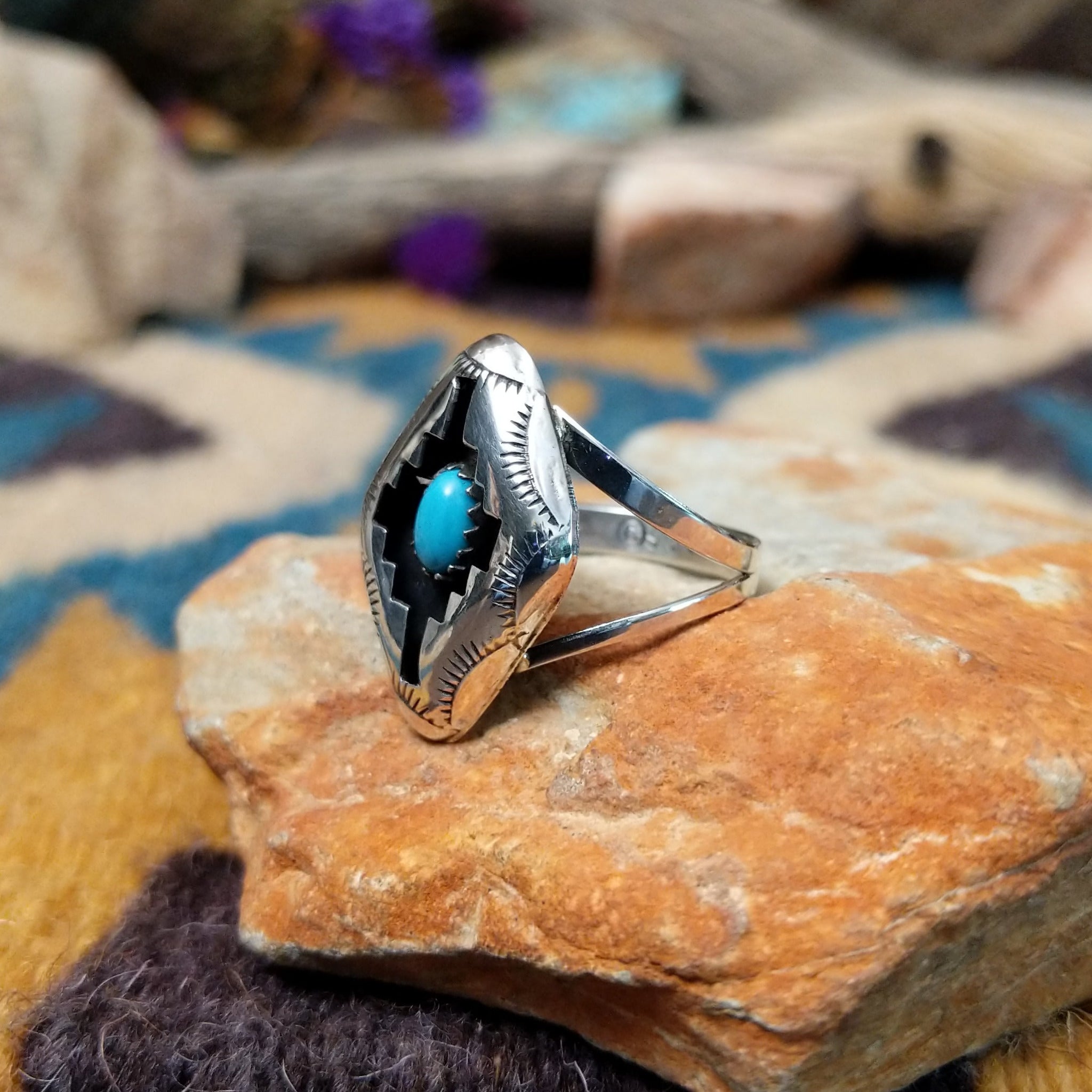 Handcrafted Navajo sterling silver shadowbox ring by P. featuring an oval turquoise cabochon set within a stepped geometric shadowbox design with hand-stamped details and an oxidized finish; side view.
