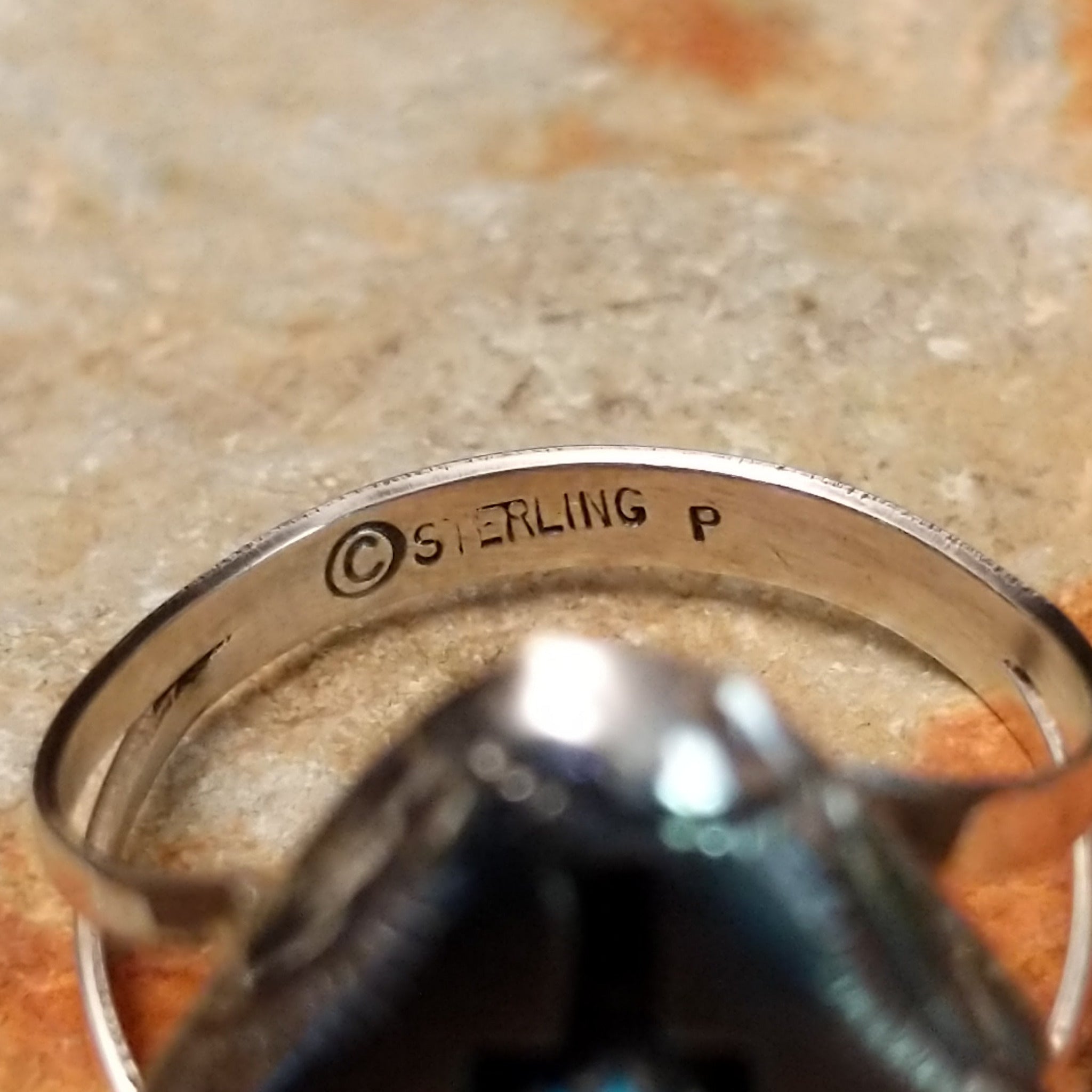 Handcrafted Navajo sterling silver shadowbox ring by P. featuring an oval turquoise cabochon set within a stepped geometric shadowbox design with hand-stamped details and an oxidized finish; artisan and Sterling Silver stamp.