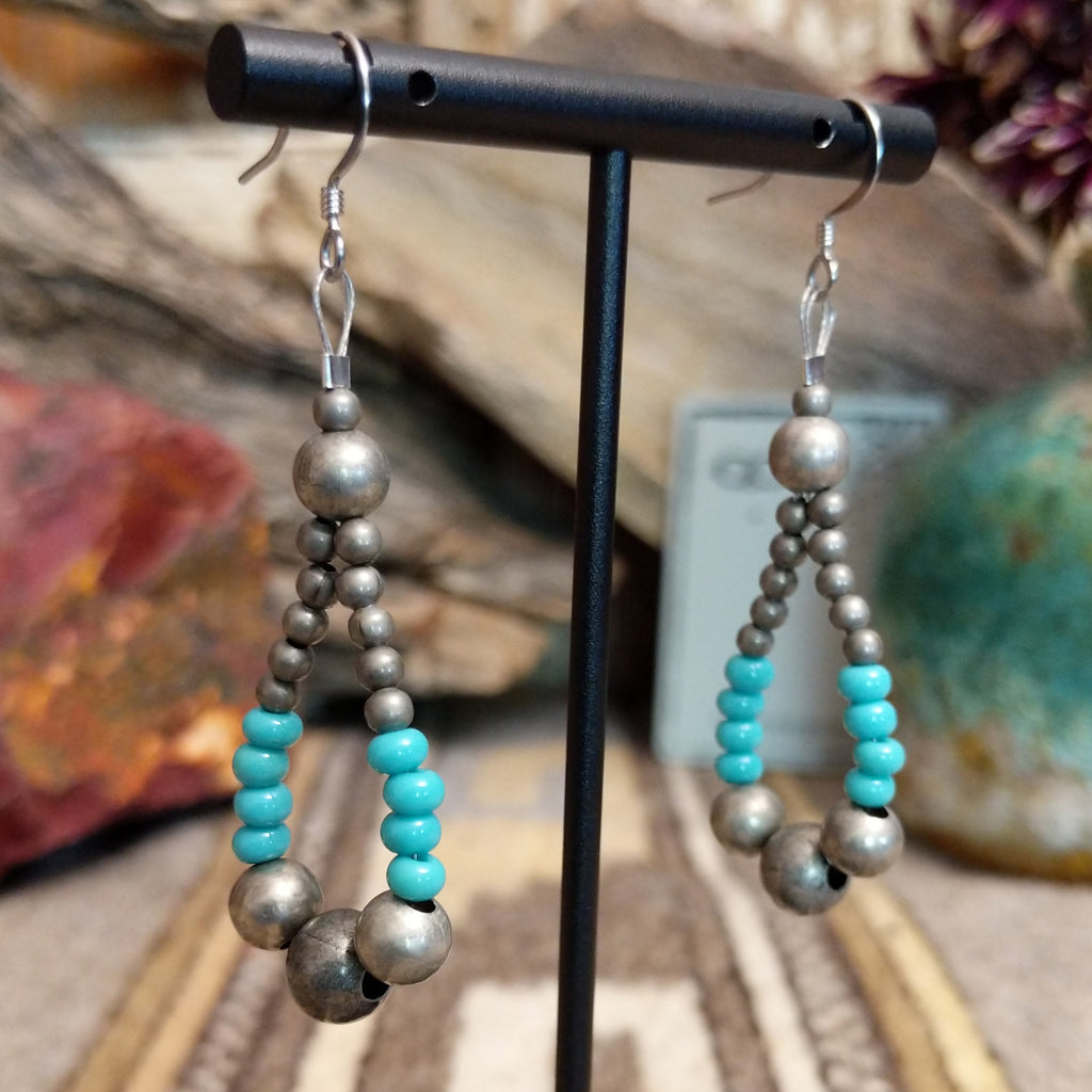 A pair of earrings in the shape of teardrops featuring silver and turquoise beads.