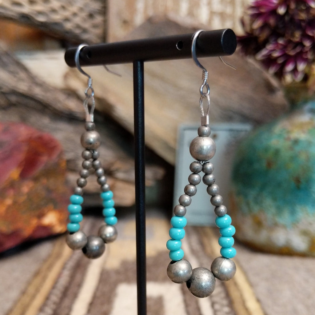 A pair of earrings in the shape of teardrops featuring silver and turquoise beads.