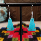 Navajo triangular turquoise slab earrings featuring bright blue stones with subtle tan and brown matrix, suspended from silver hooks; backside view.