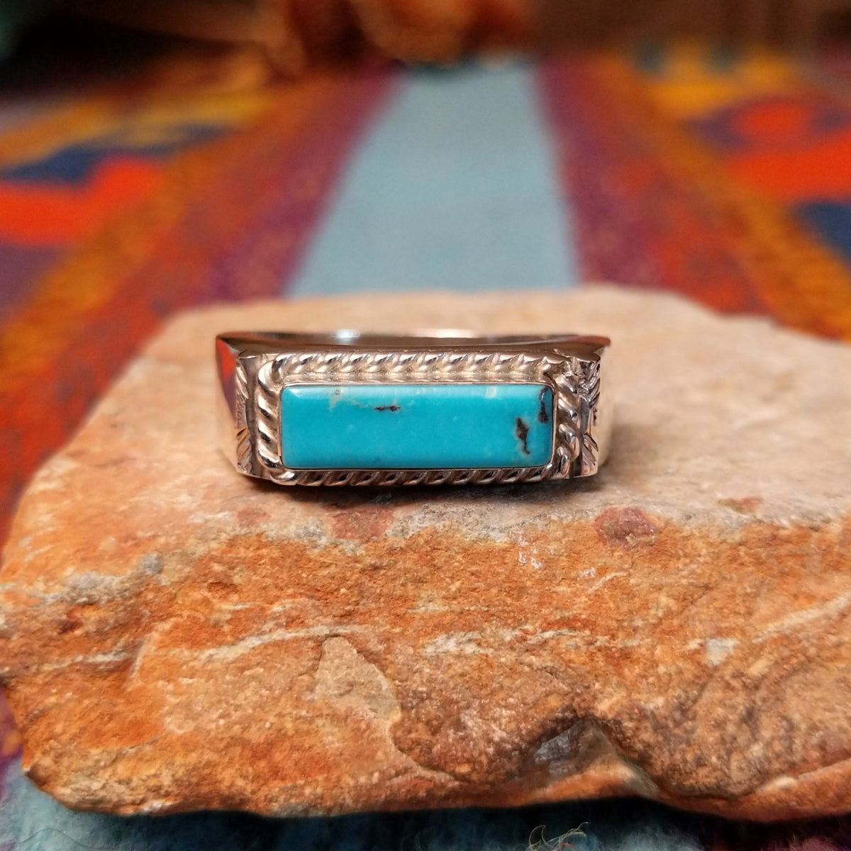 Navajo Turquoise Bar Ring by A.Q.J. featuring a rectangular bright blue turquoise stone with subtle matrix, framed by twisted-rope silverwork and decorative stamped details.
