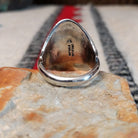 Navajo silver ring featuring a dark bear claw, oval turquoise stone, and detailed feather, scroll, and bead-style silverwork in an elongated statement design; underside view.