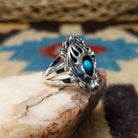 Navajo turquoise bear paw shadowbox ring, featuring a round blue turquoise stone set in a handcrafted sterling silver bear paw design with a dimensional shadowbox setting.  Side view.
