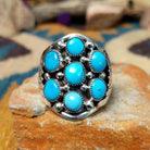 Sterling silver Navajo turquoise cluster ring featuring seven turquoise cabochons, serrated bezels, silver raindrop accents, and a classic Southwestern floral cluster design.