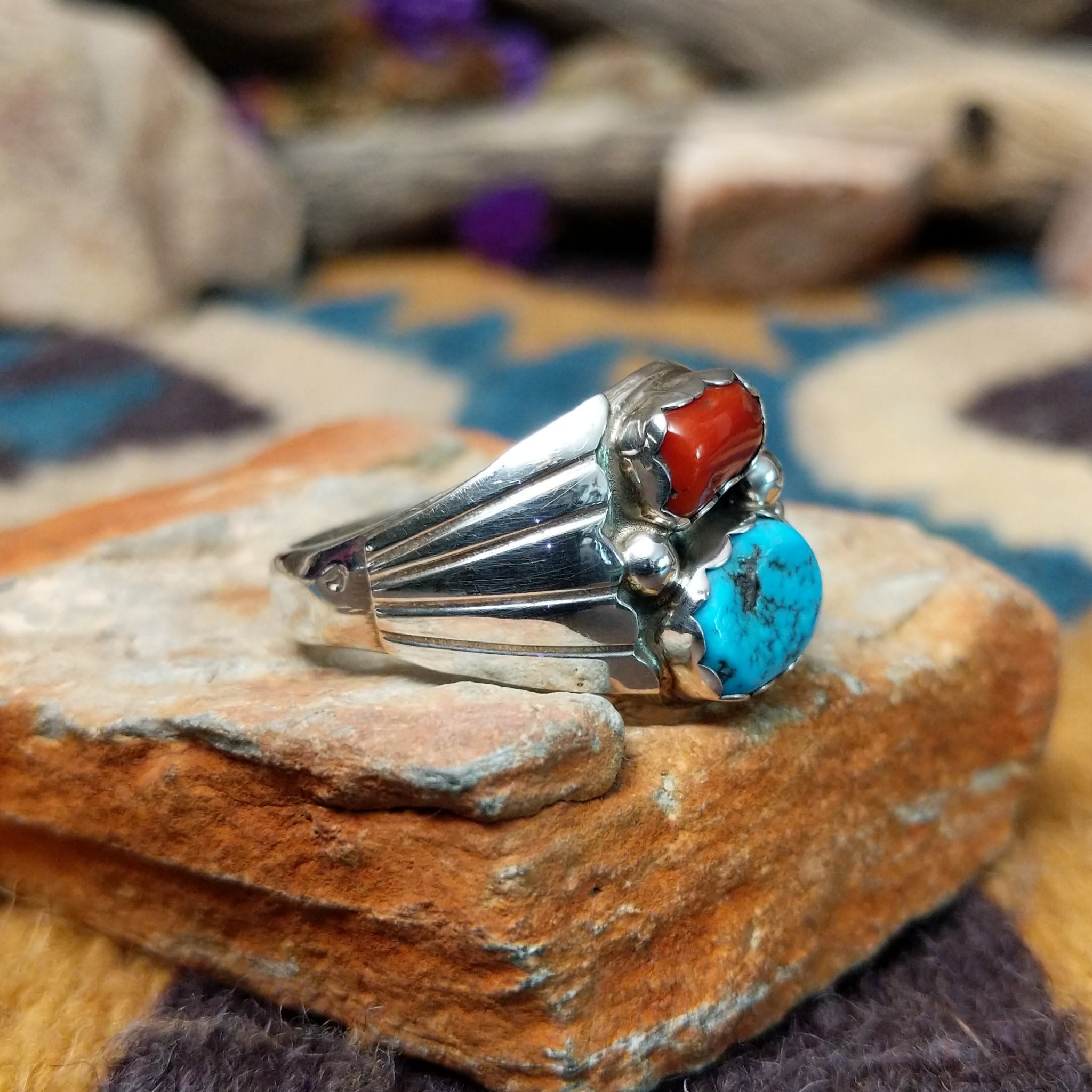 Sterling silver Navajo ring by S. featuring genuine turquoise and red coral cabochons, silver raindrop accents, and a split-shank Southwestern design; side view.