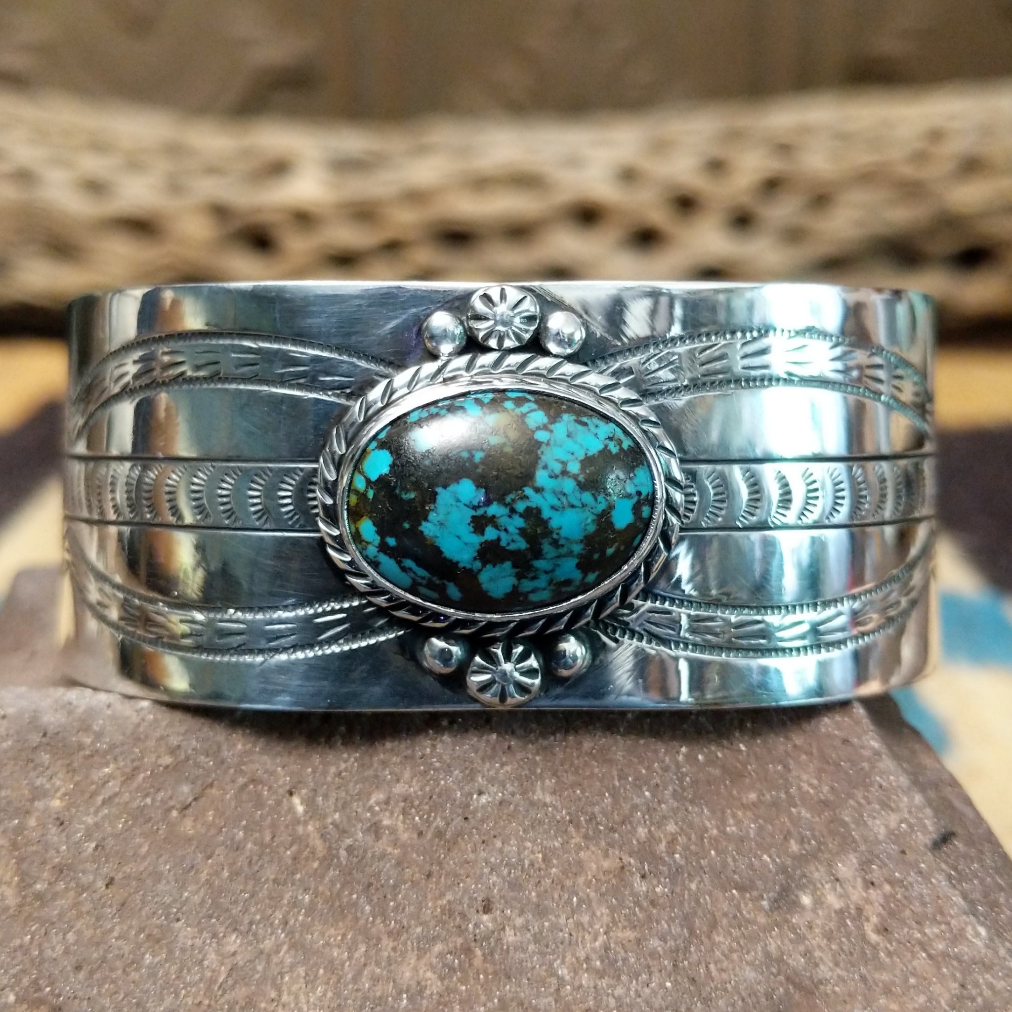 Navajo turquoise cuff by L.T.C., featuring an oval blue turquoise stone with natural black matrix set in a handcrafted sterling silver cuff with hand-stamped details, decorative silver accents, and a twisted rope bezel.