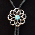 Navajo Turquoise Flower Bolo Tie by M. featuring an openwork silver flower with a round turquoise center stone, braided black leather cord, and polished silver tips.