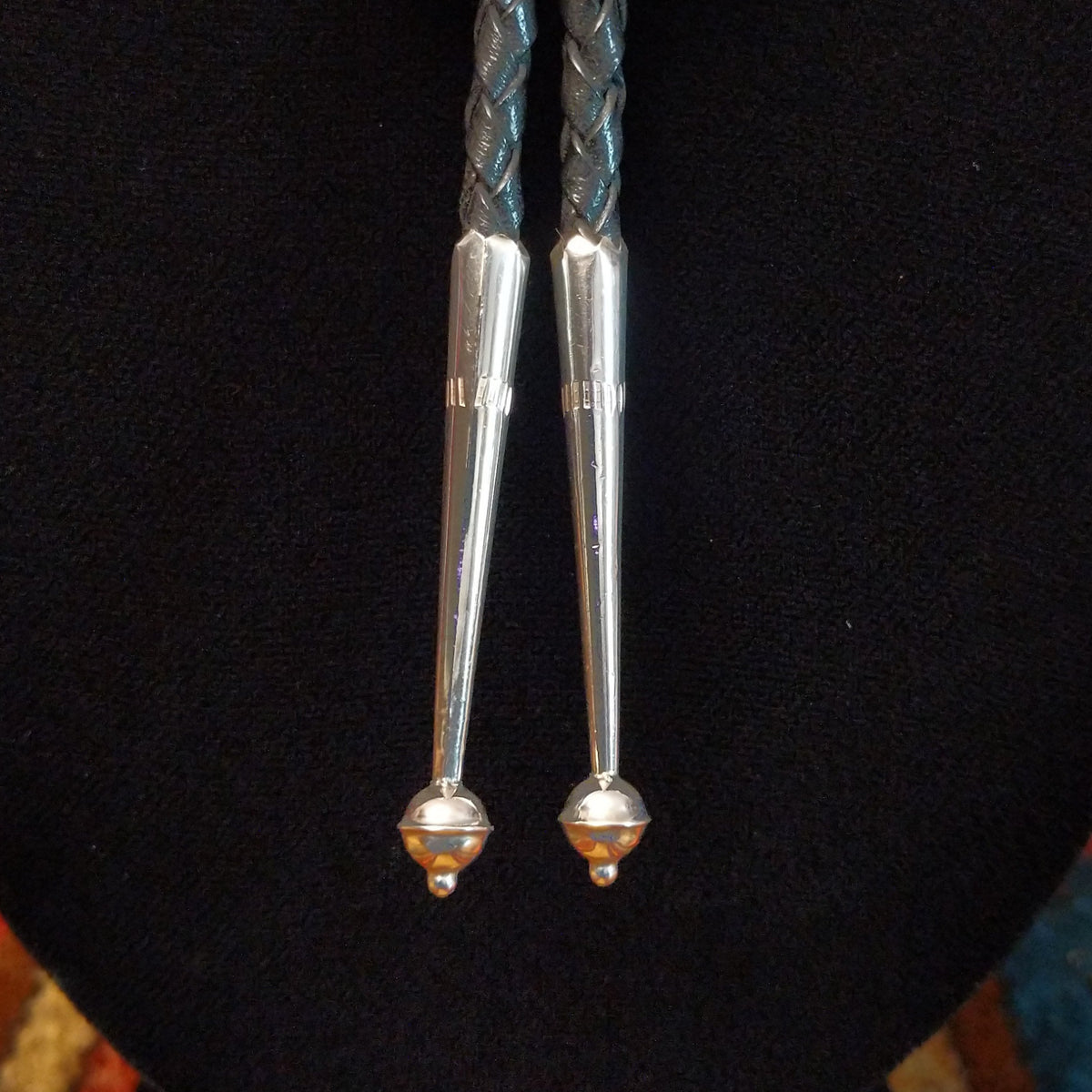 Navajo Turquoise Flower Bolo Tie by M. featuring an openwork silver flower with a round turquoise center stone, braided black leather cord, and polished silver tips; tips view.