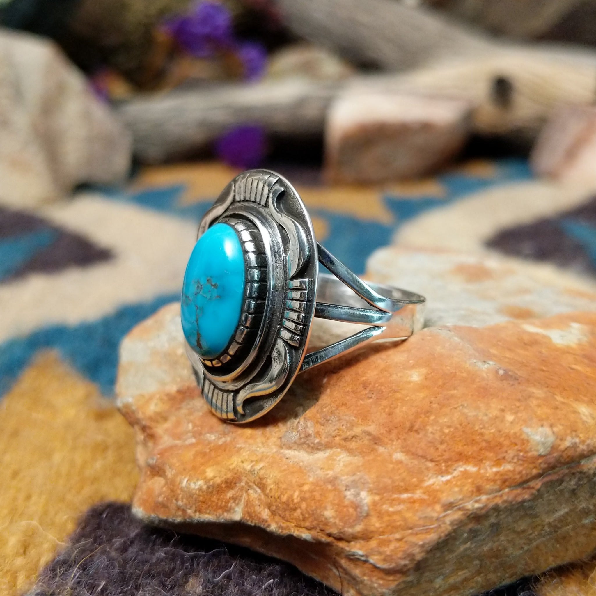 Sterling silver Navajo turquoise ring by J.M.N. with an oval sky-blue stone and hand-stamped horn design; side view.