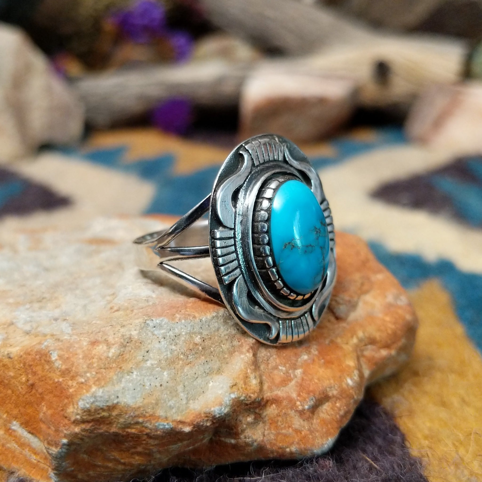 Sterling silver Navajo turquoise ring by J.M.N. with an oval sky-blue stone and hand-stamped horn design; side view.