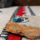 Navajo turquoise inlay ring featuring bright blue turquoise with dark matrix, segmented by polished silver channels across a wide silver band; side view.
