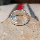 Navajo turquoise inlay ring featuring bright blue turquoise with dark matrix, segmented by polished silver channels across a wide silver band; underside view.
