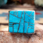 Sterling silver ring featuring a rectangular turquoise inlay and geometric channel work.
