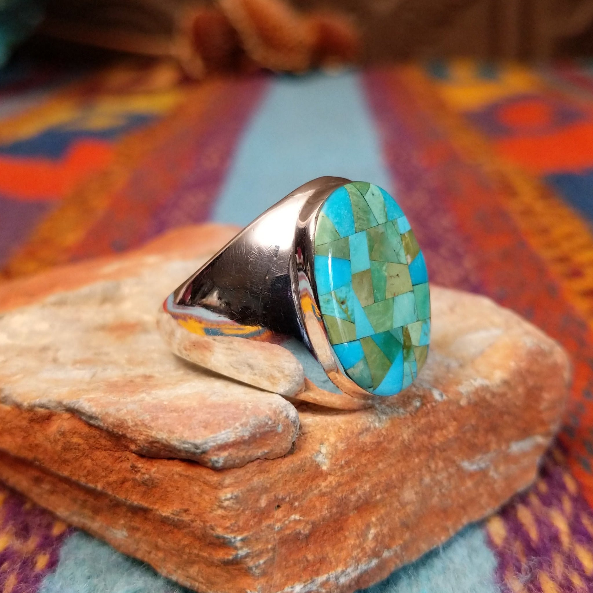 Navajo Turquoise Mosaic Ring featuring an oval face filled with geometric turquoise pieces in blue, aqua, sage, and green tones, set in a wide polished silver band; side view.
