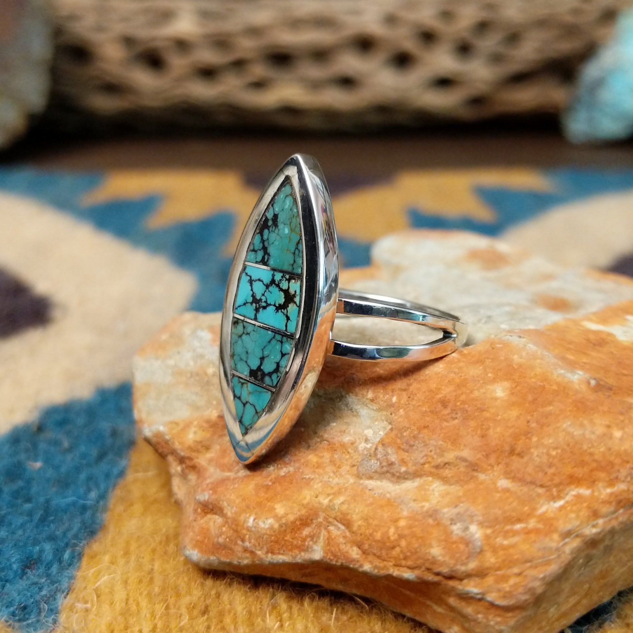 Handcrafted Navajo sterling silver navette ring featuring an elongated turquoise inlay with natural black matrix, set in a polished bezel with a split shank design; side view.
